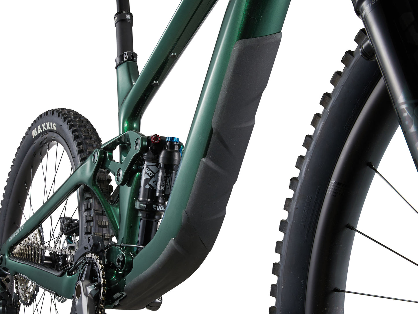 Close-up of a green mountain bike with focus on suspension fork and tire tread.